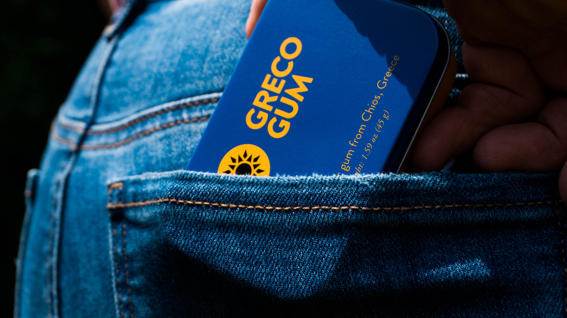 Brand photography Photo of someone grabbing a Greco Gum tin from the back pocket of their jeans